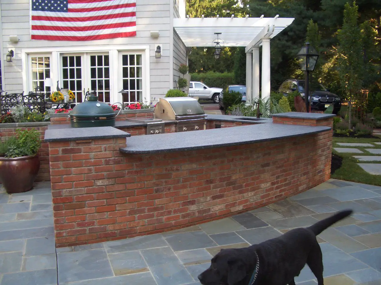 Outdoor brick bar with countertop and American flag in background.
