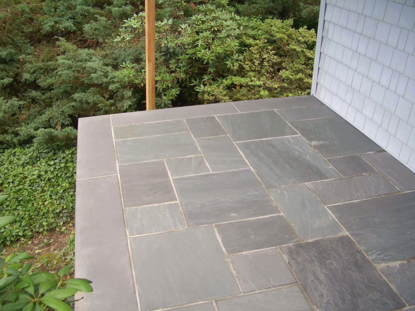 A stone tile patio with a geometric pattern beside a house.