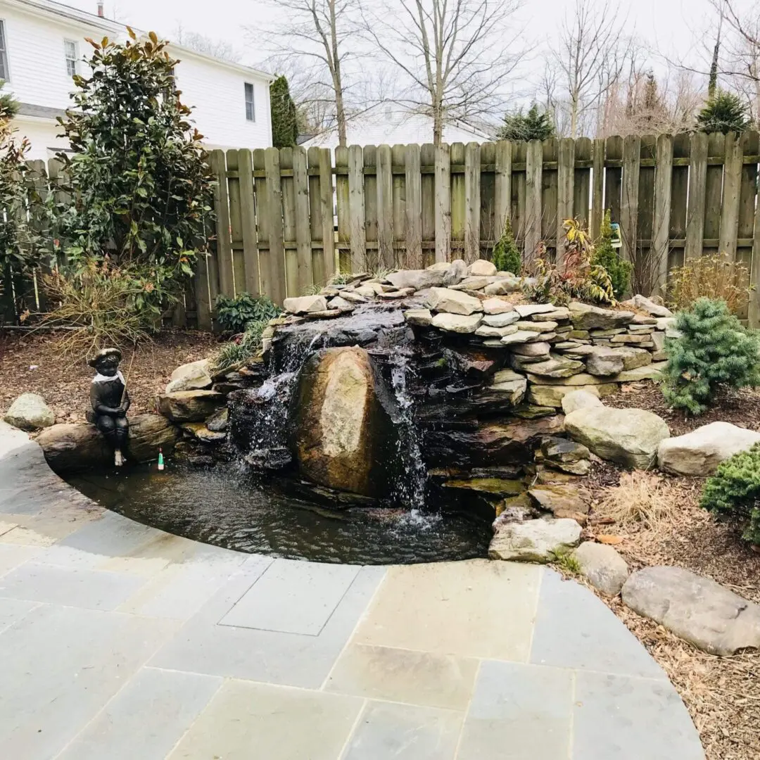 A serene backyard waterfall feature with natural stones and flowing water.