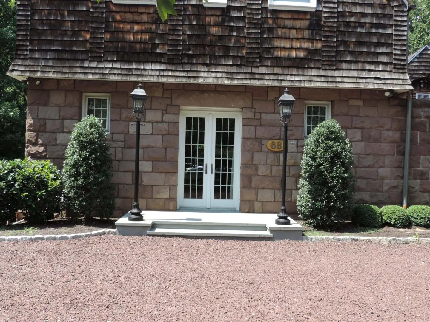 White double door entrance with flanking bushes and stone steps.