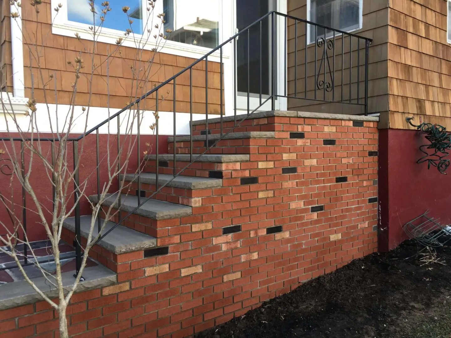 Brick staircase with a unique pattern and metal railing.