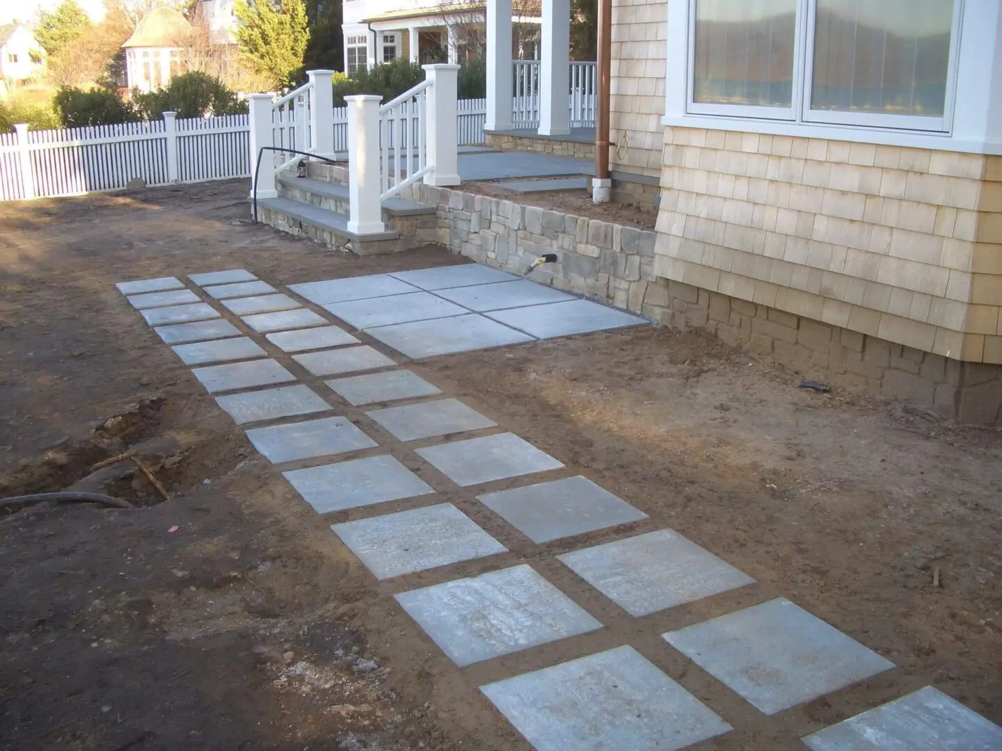 Concrete slabs forming a pathway beside a house under construction.