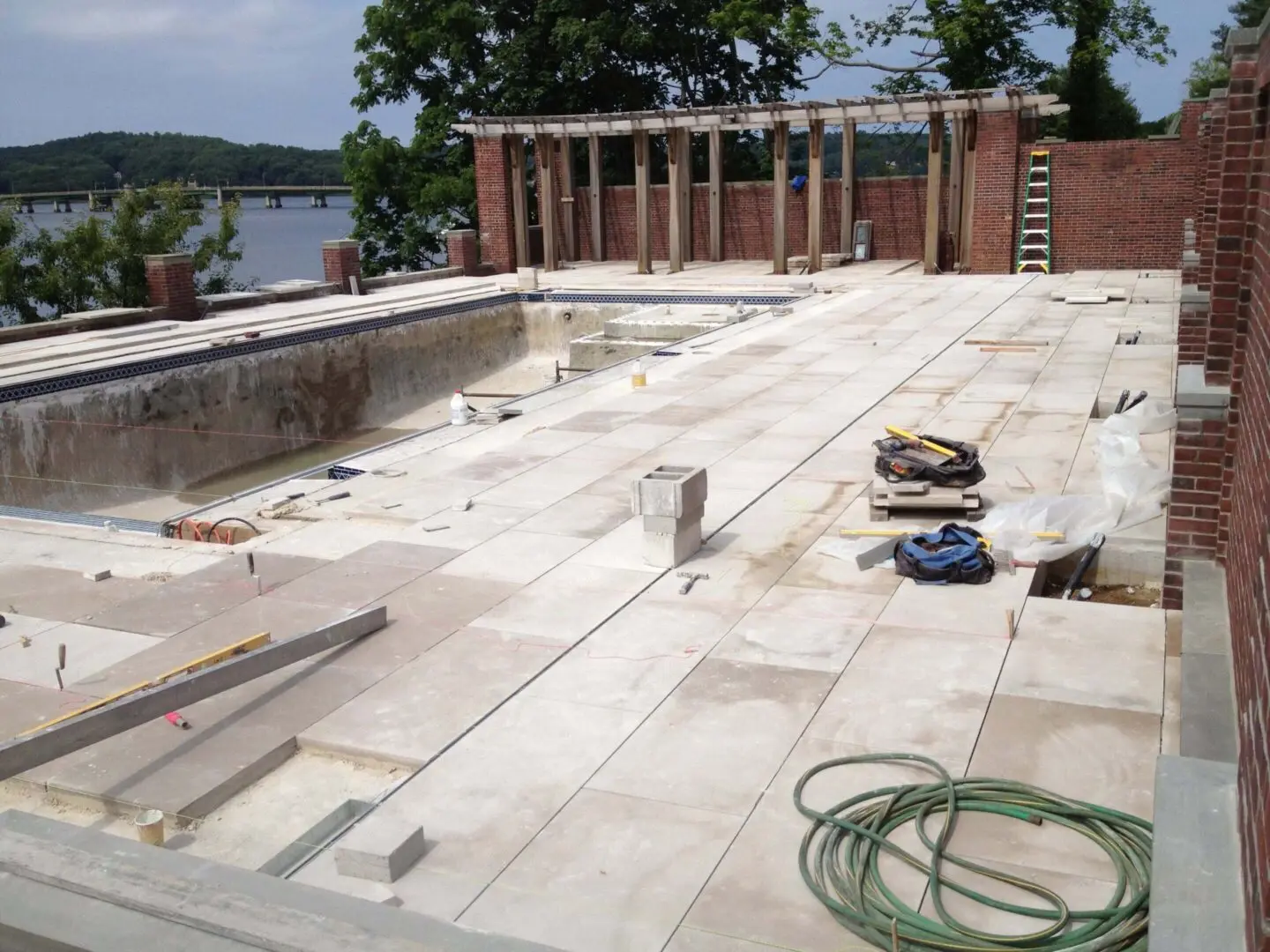 An empty swimming pool under construction with tools and materials scattered around.