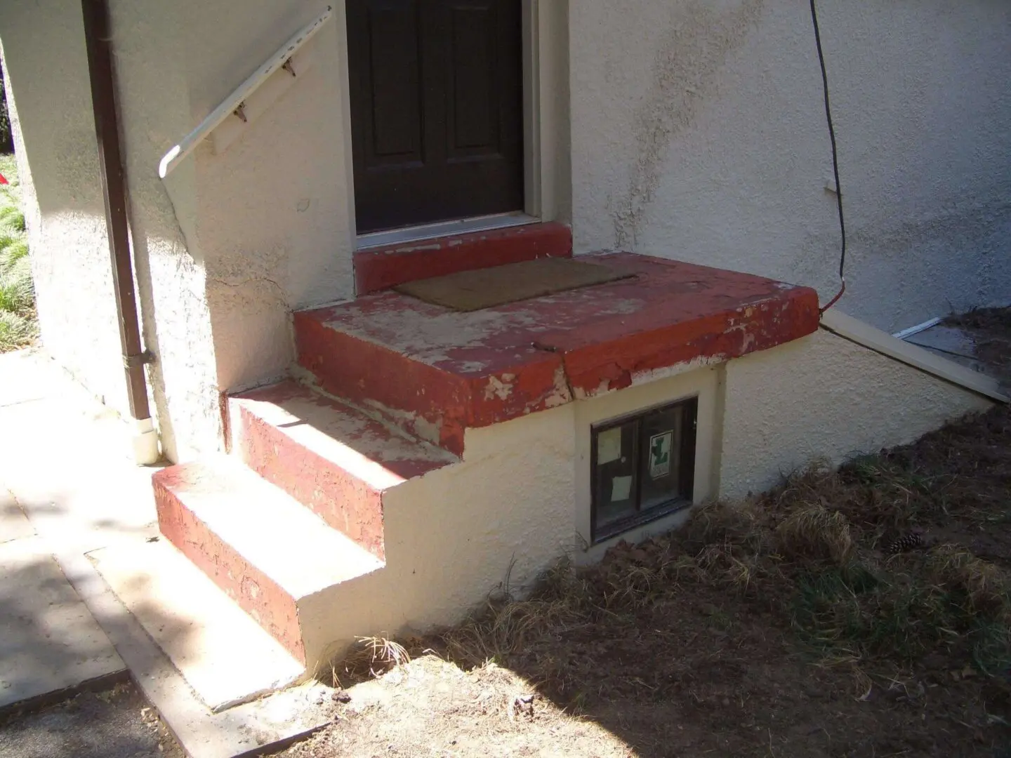 Small basement entrance with stairs and a landing covered in red material.