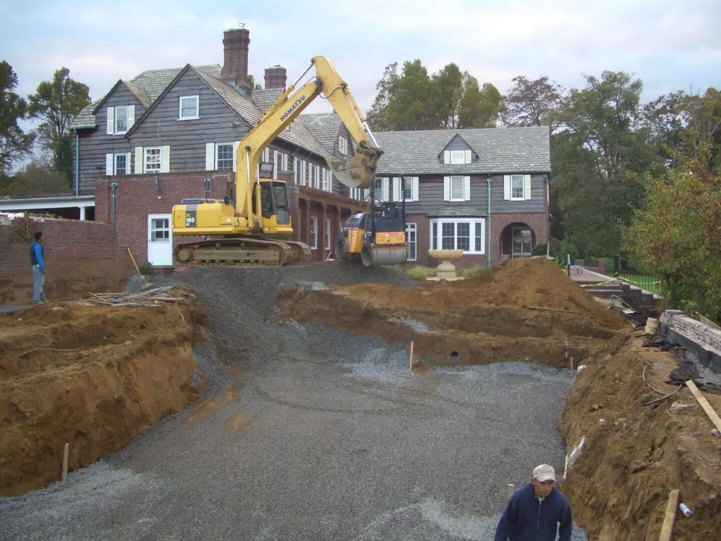 Excavator digging foundation at residential construction site.
