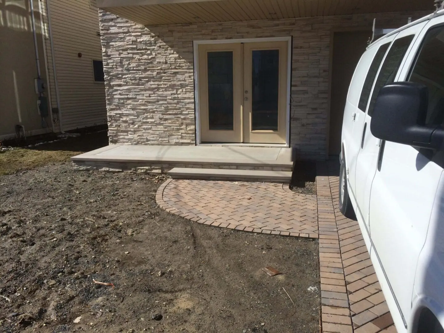 Newly paved stone pathway leading to a backdoor with a stone wall.
