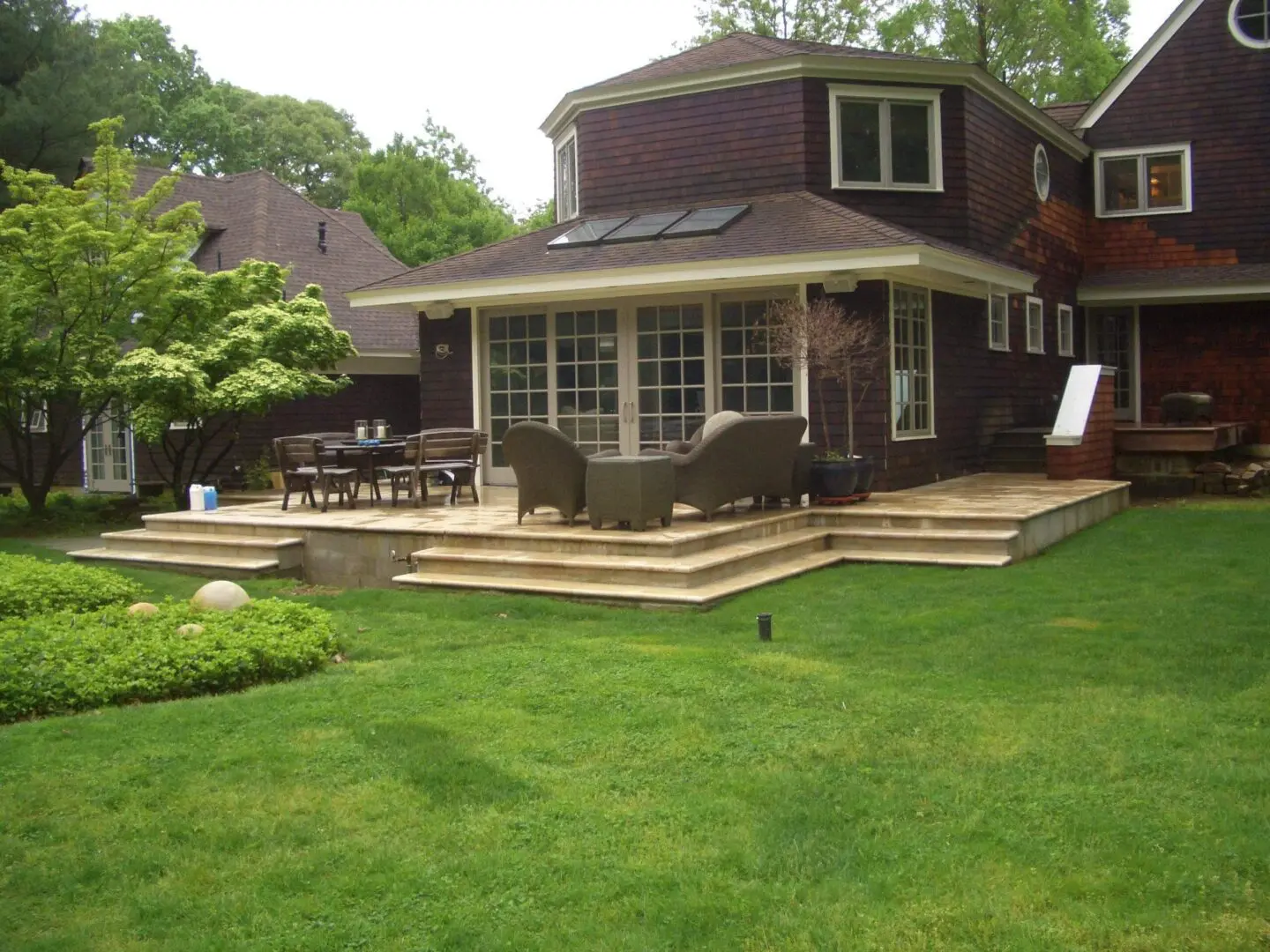 A spacious backyard with a brown house and wooden deck.