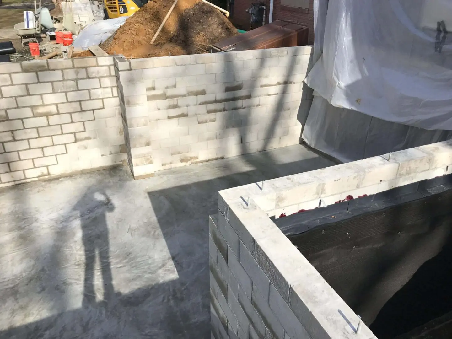 A partially constructed brick structure with shadow of a person.