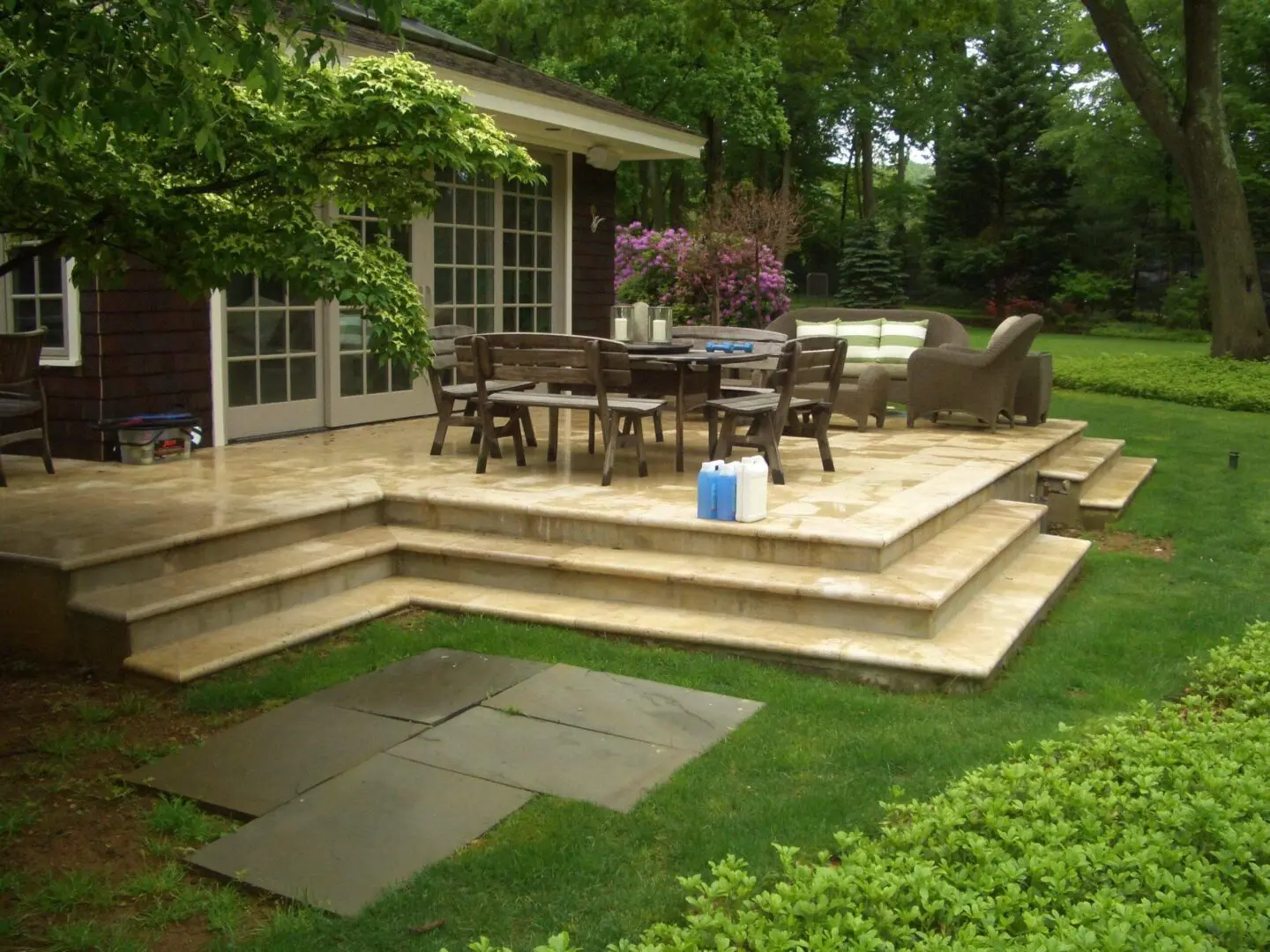 Elegant outdoor patio with multi-level stone steps and wooden furniture.