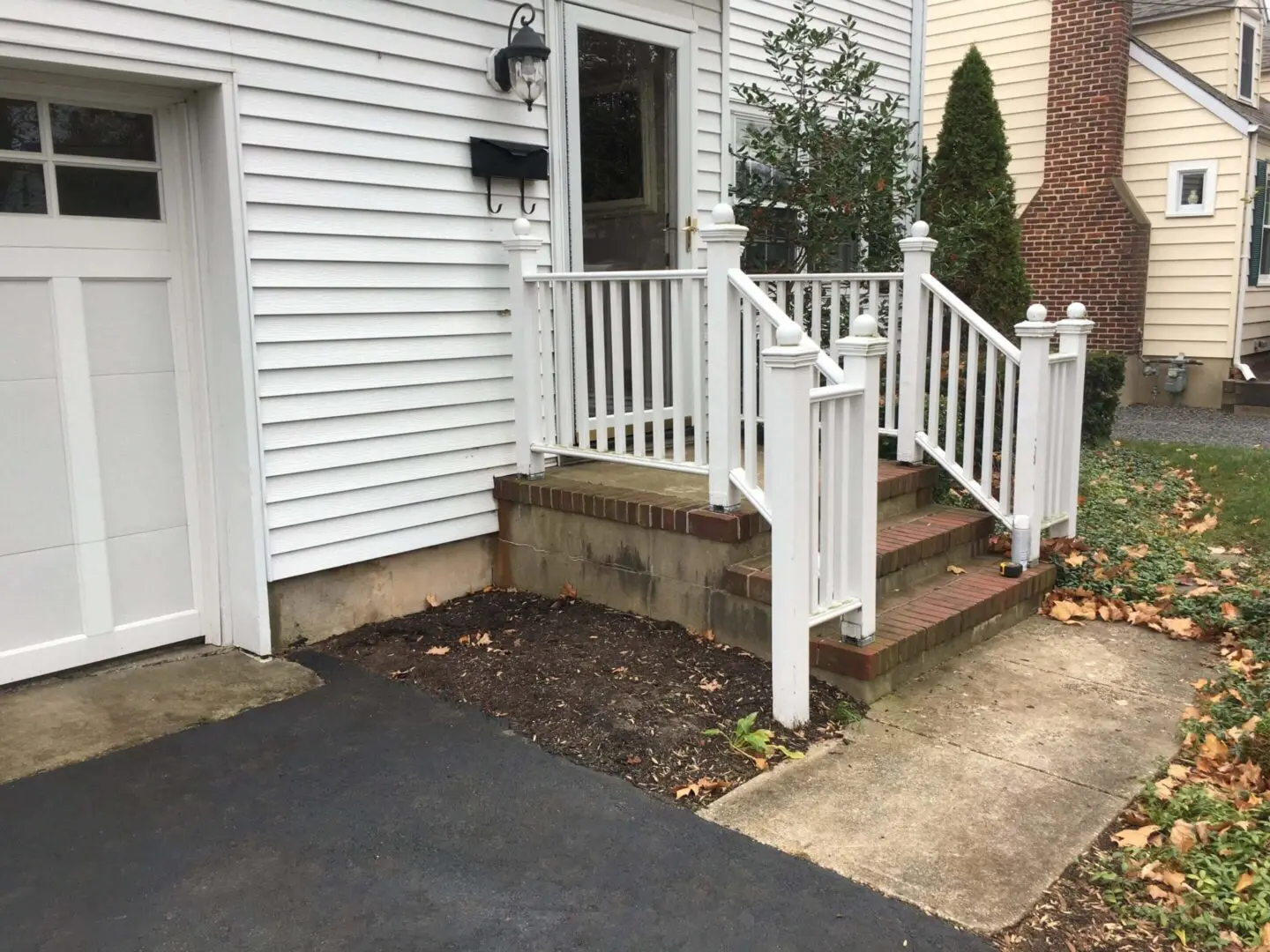 Broken concrete steps with white railing beside a house.