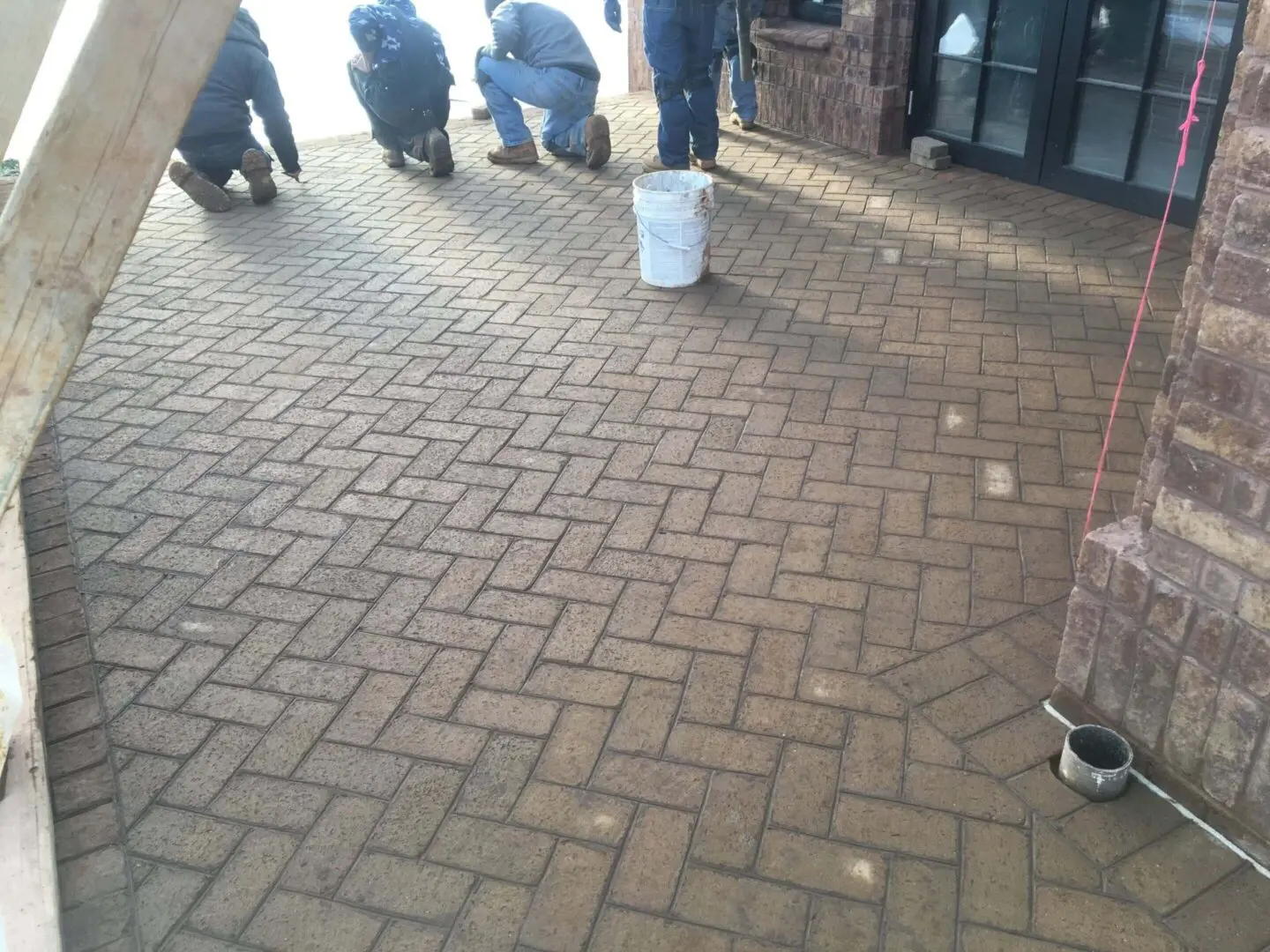 People gathered on a brick-paved area with a white bucket in the center.