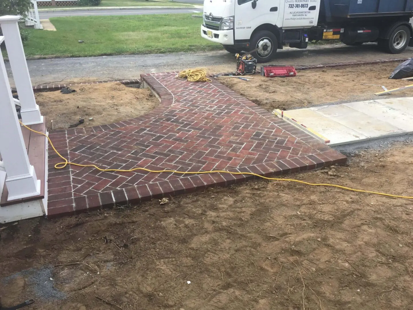 Newly laid patterned brick pavement next to a truck at a construction site.