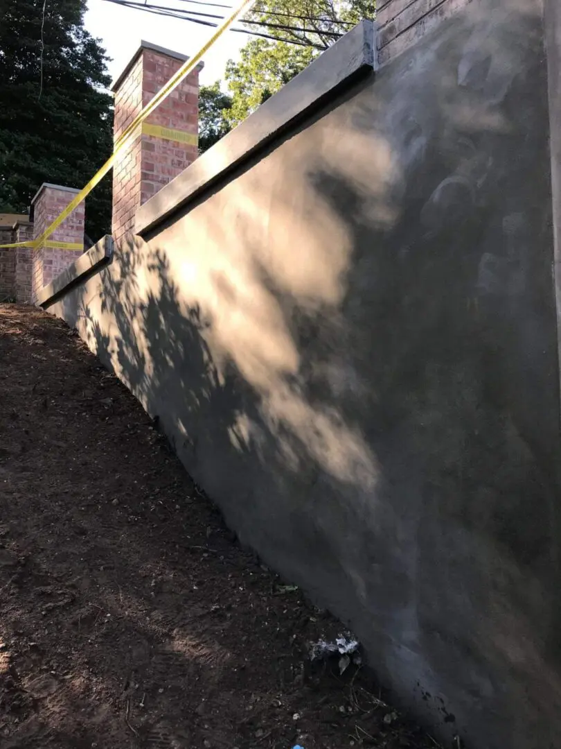 A newly constructed concrete retaining wall alongside a sloped ground.