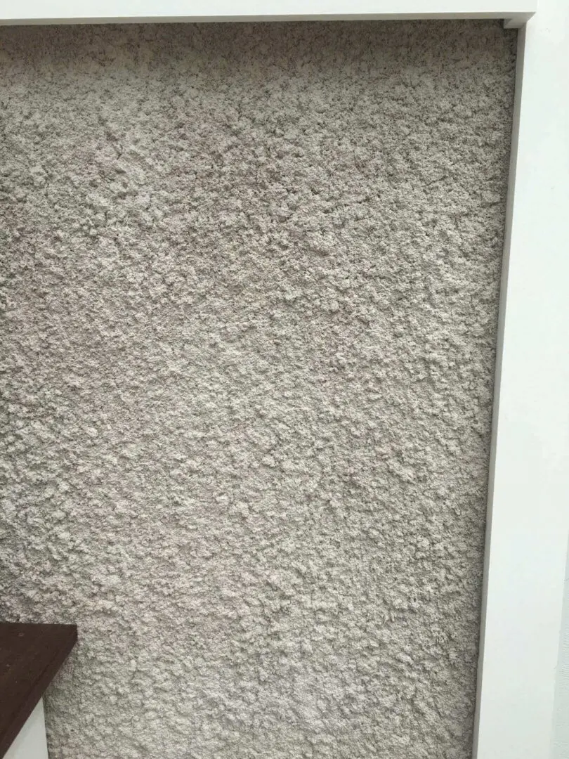 Close-up of textured gray wall next to a white frame.