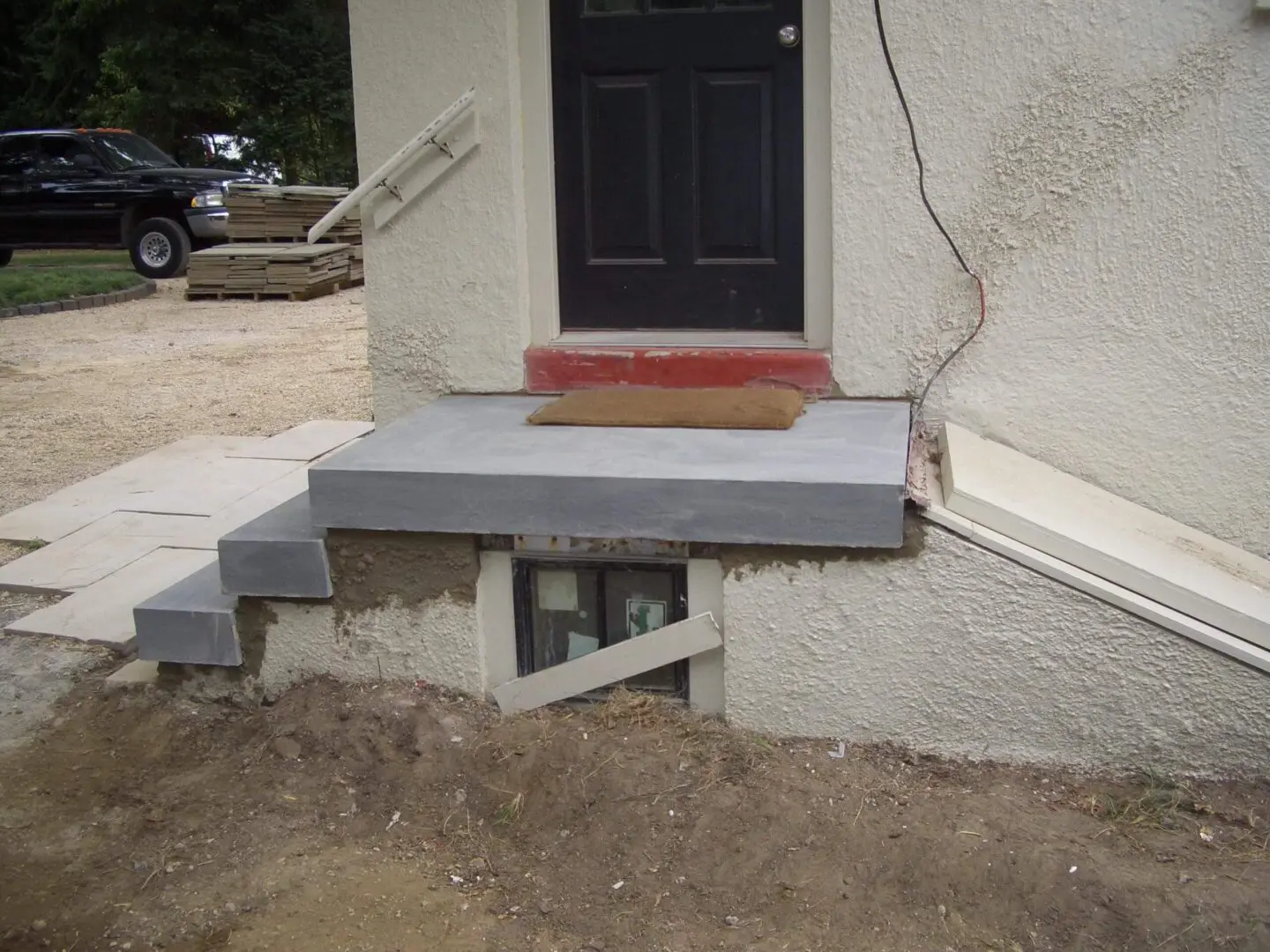 Concrete steps and landing leading to a black door on a white building.