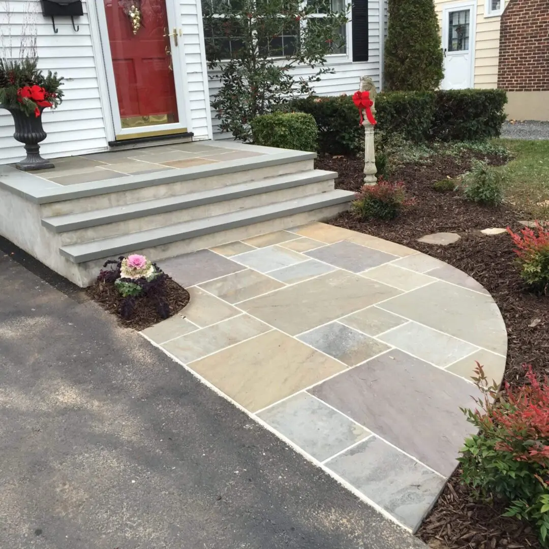 Elegant stone pathway leading to a house entrance with steps and red doors.