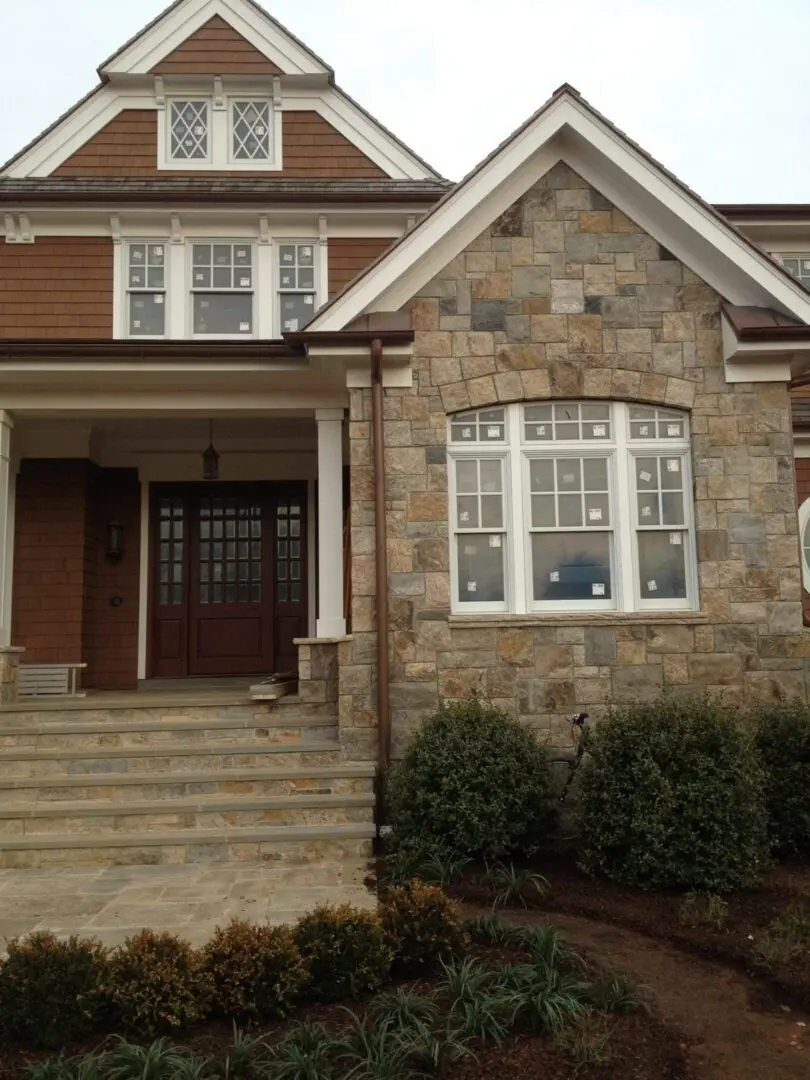 Stone and brick house with steps leading to a covered porch.