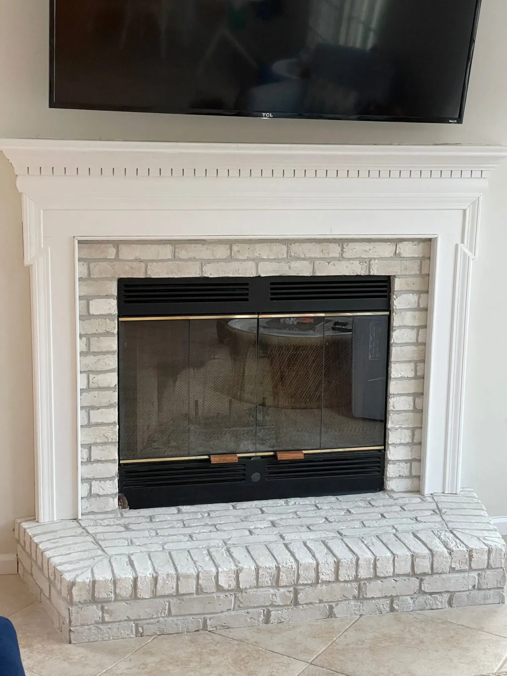 White brick fireplace with black glass doors beneath a mounted TV.