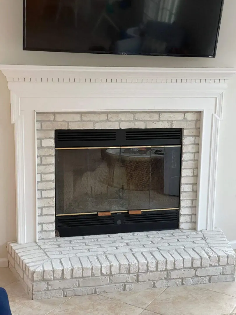 White brick fireplace with glass doors beneath a mounted TV.