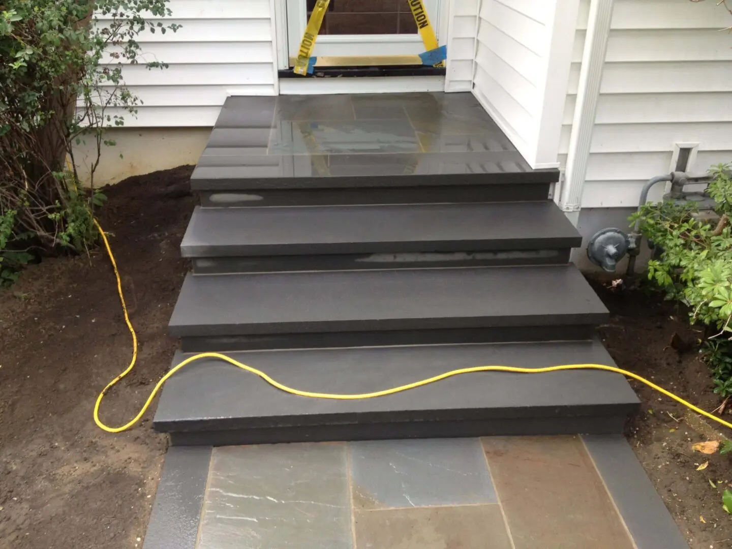 Newly painted dark gray stairs with a yellow extension cord.