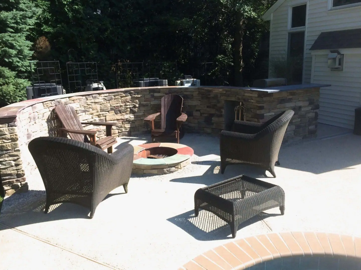 Outdoor patio with chairs and fire pit on a sunny day.