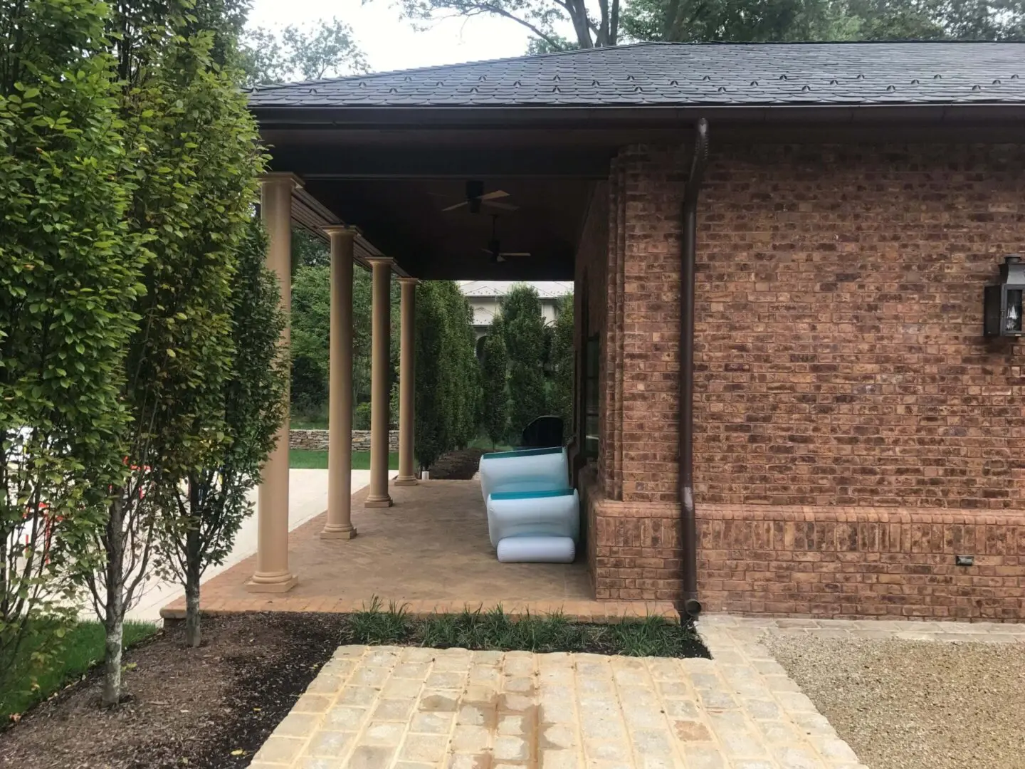 Brick house with a covered patio and cushioned seating area.