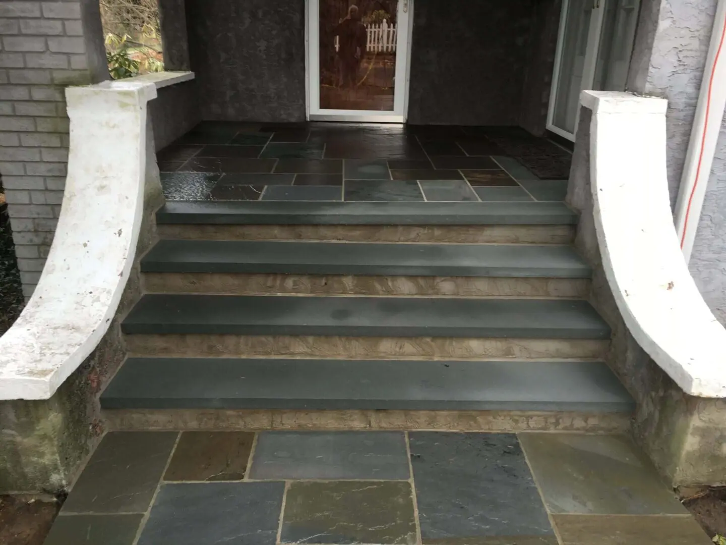 Stone steps leading to a dark doorway with curved white railings.