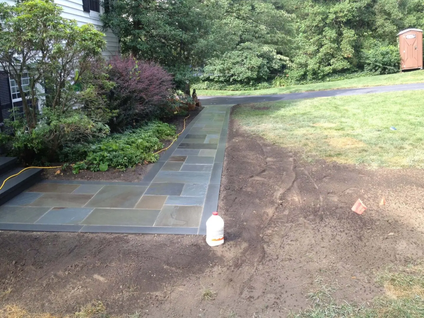 Newly installed stone pathway beside a garden and lawn.