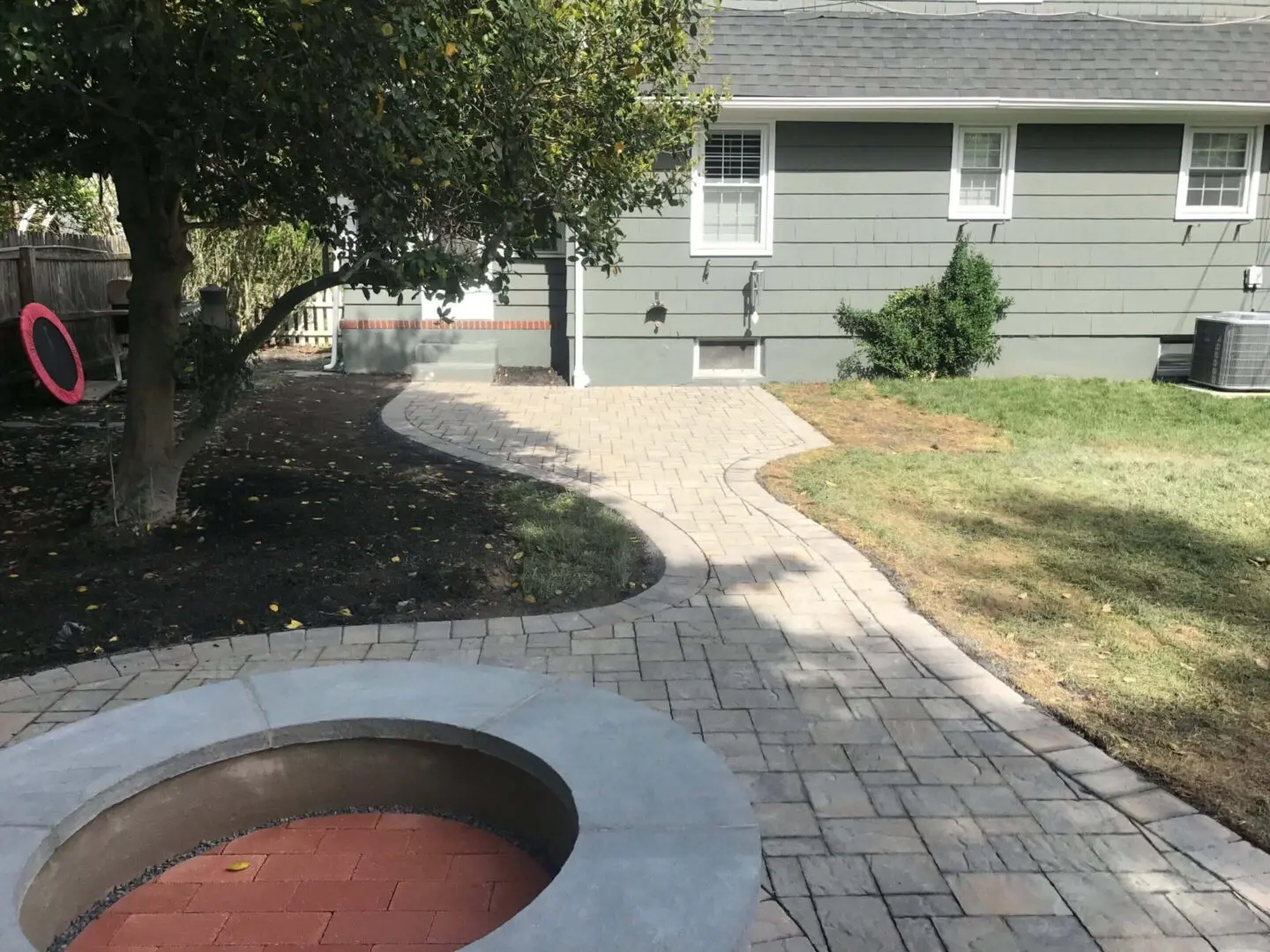 Curved stone pathway leading to a gray house with a front porch.