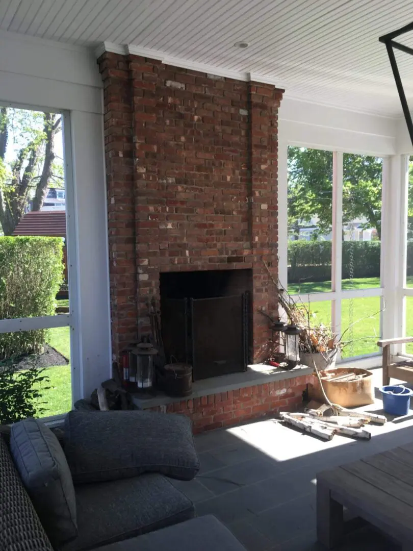 Cozy indoor fireplace with a brick surround and large windows.