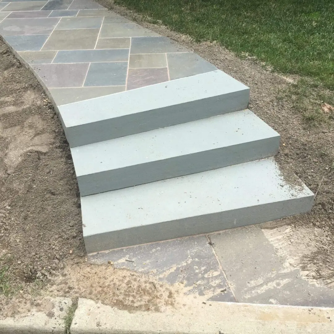 Newly constructed concrete steps leading to a paved walkway.
