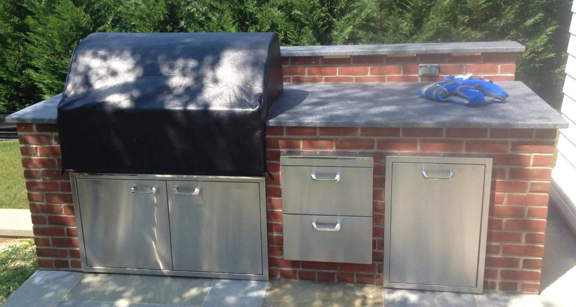 Outdoor kitchen setup with stainless steel appliances and a brick base.