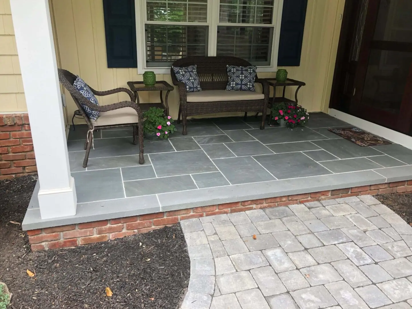 Cozy outdoor seating area with stone flooring and cushioned chairs.