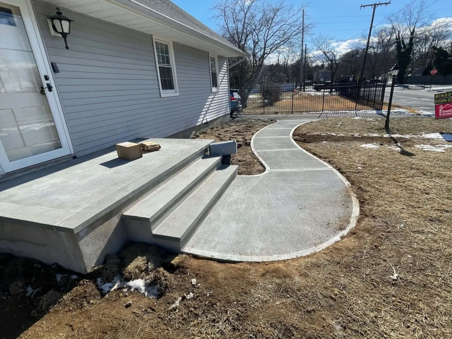 New concrete patio with steps and a curved walkway beside a house.