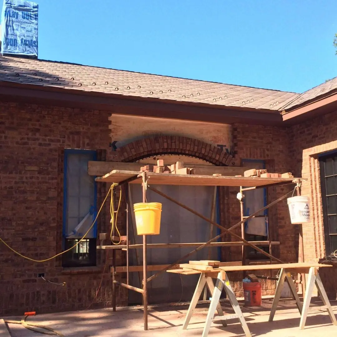Construction scaffolding set up outside a brick building under clear blue sky.