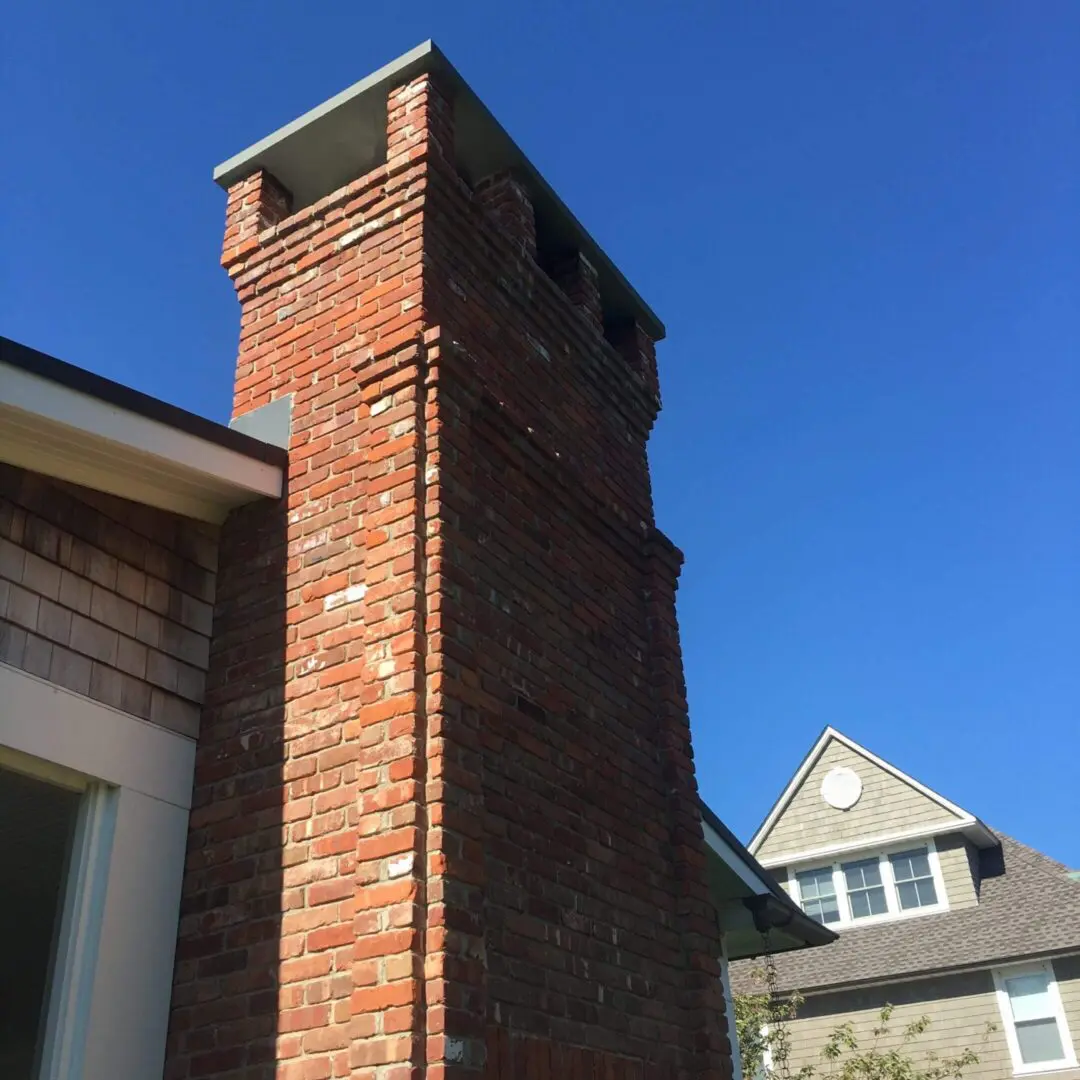 Tall brick chimney against a clear blue sky.