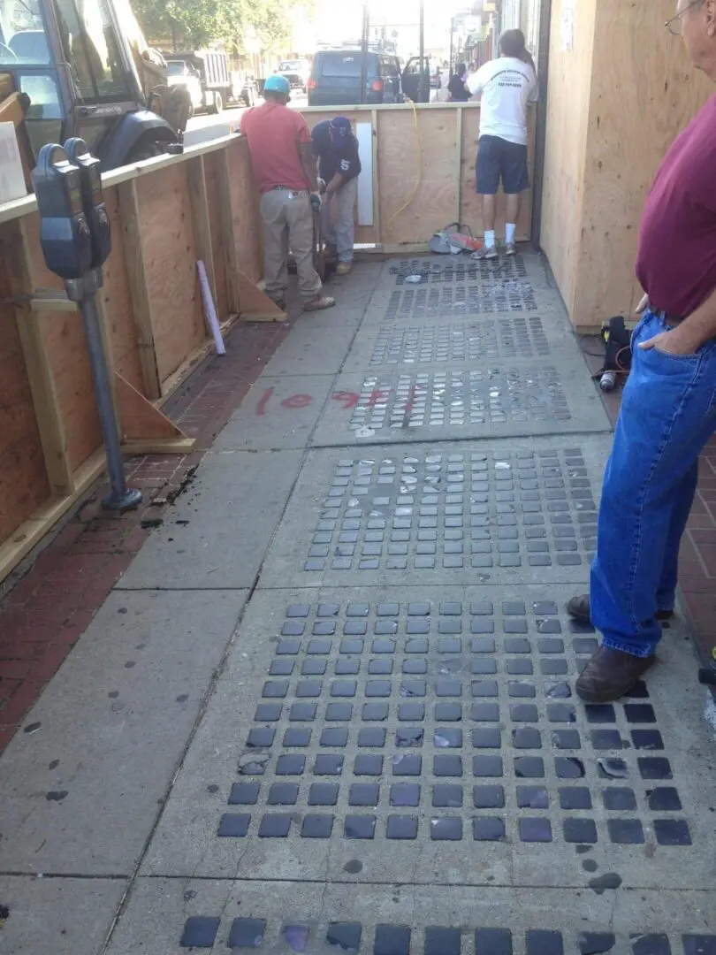 Workers installing a metal floor grid in an industrial setting.