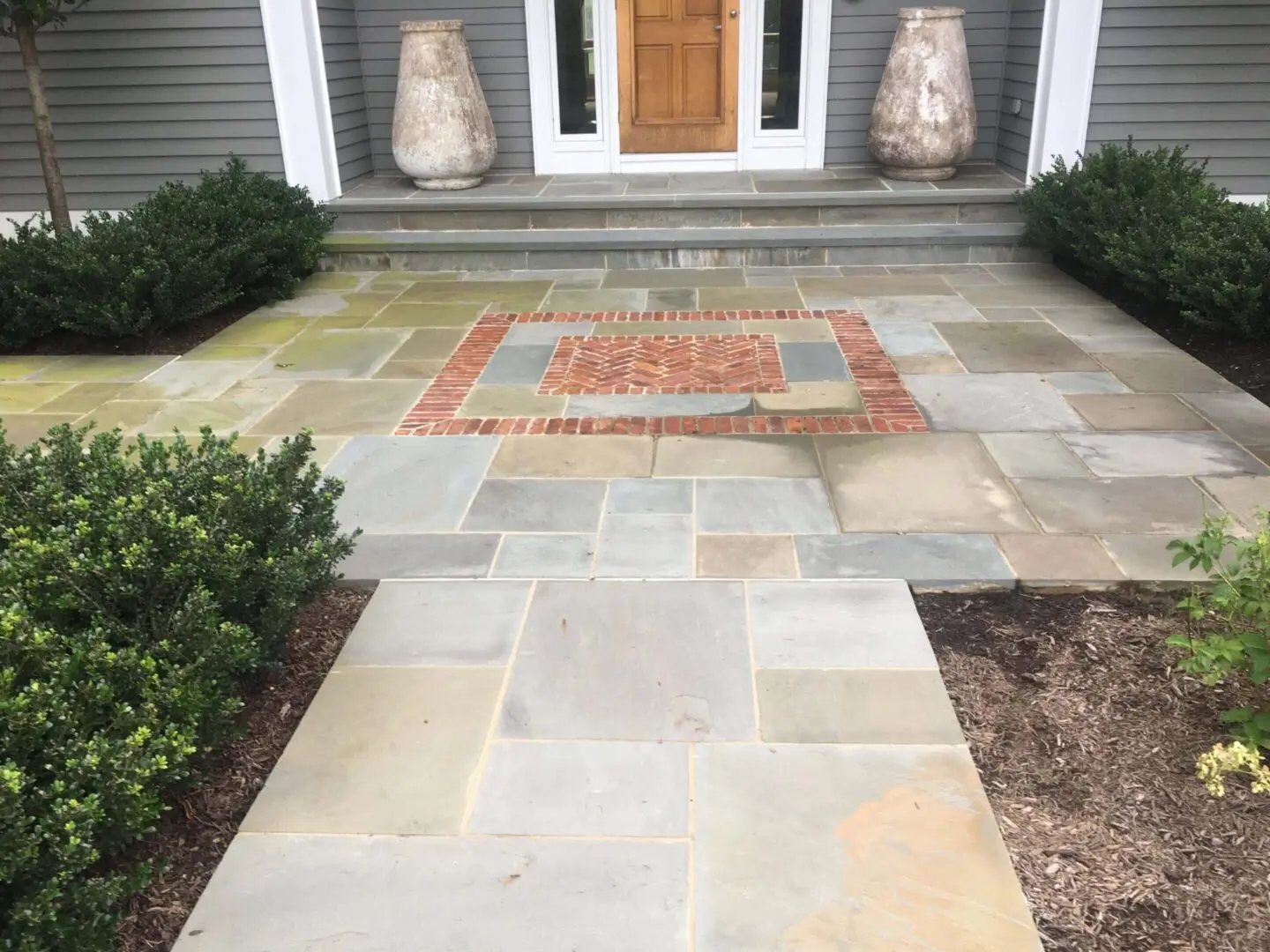 A stone-paved walkway with a decorative brick pattern near the entrance.