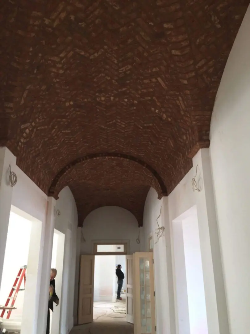 Historic hallway with a detailed brick vaulted ceiling.