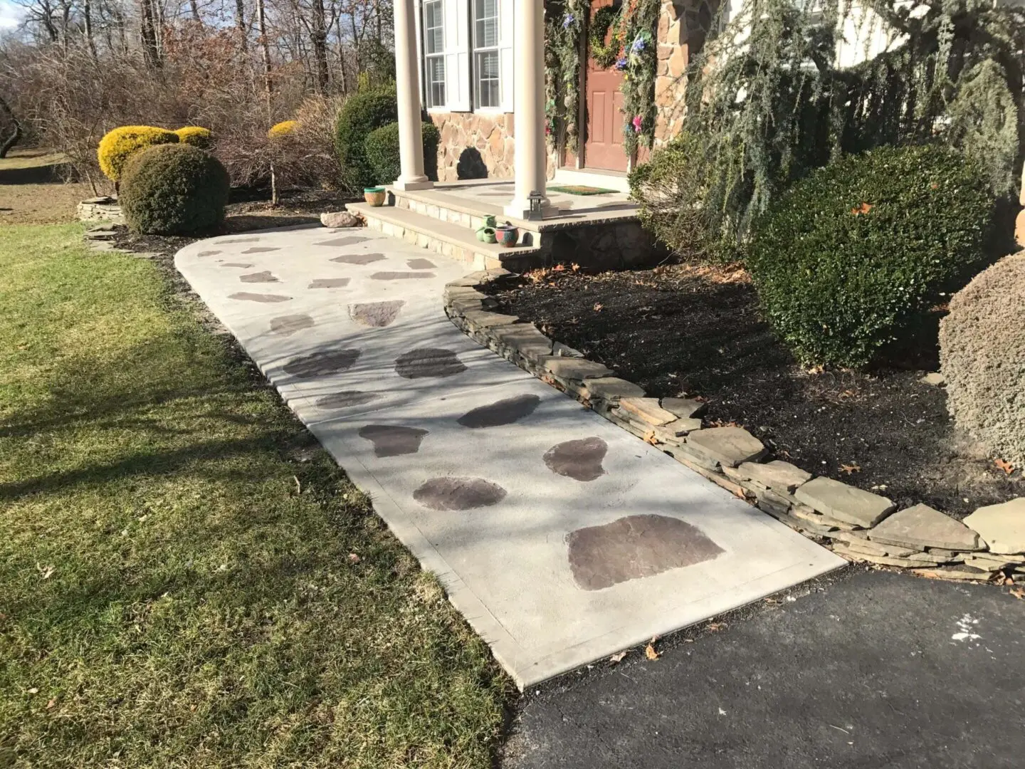 A stone pathway leading to a brick house with landscaping on the side.