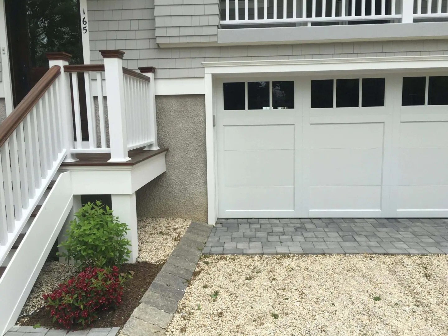 Newly installed white garage door with fresh gravel driveway and stone border.