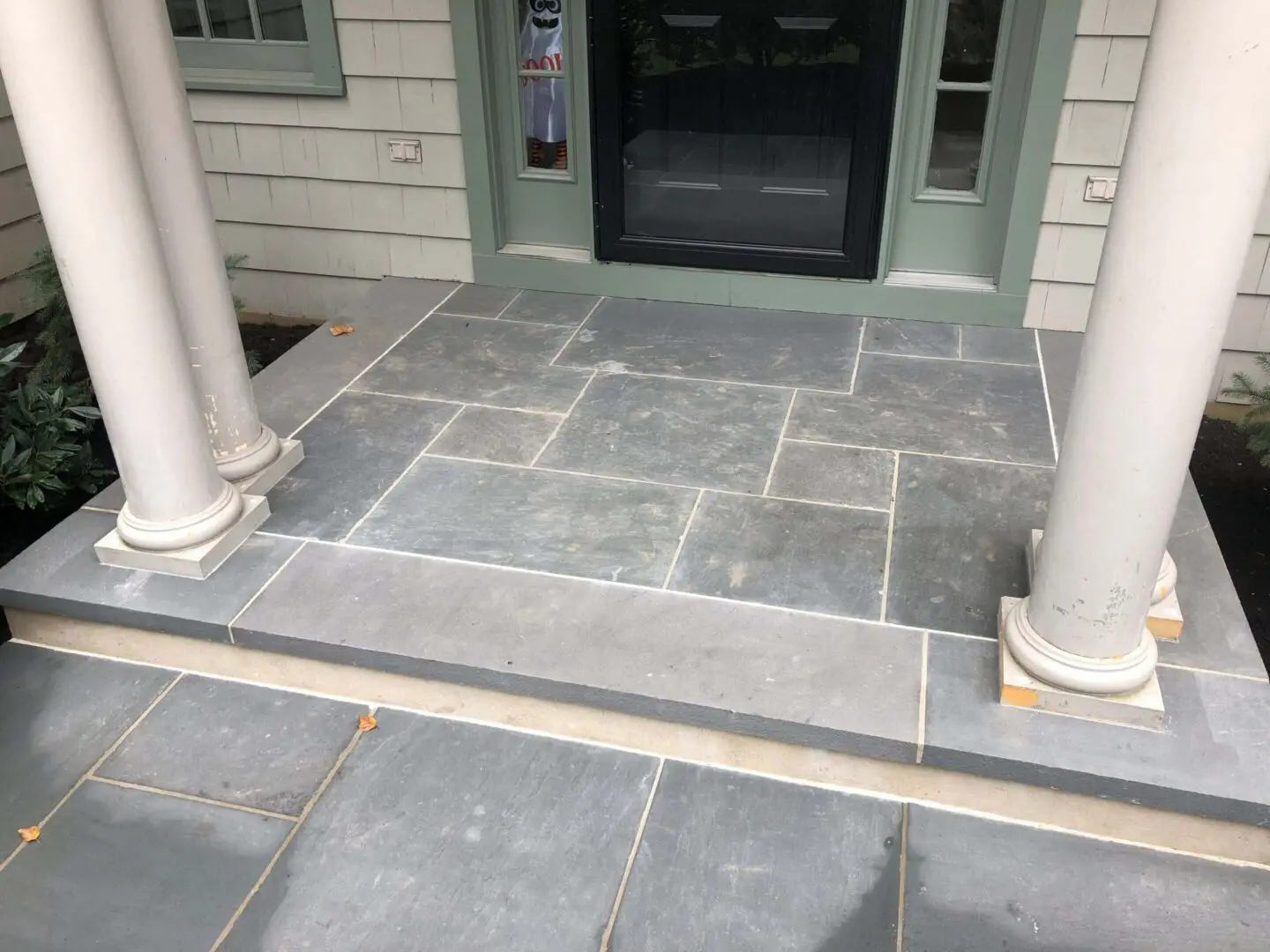 Stone tile porch with steps and columns at entrance.