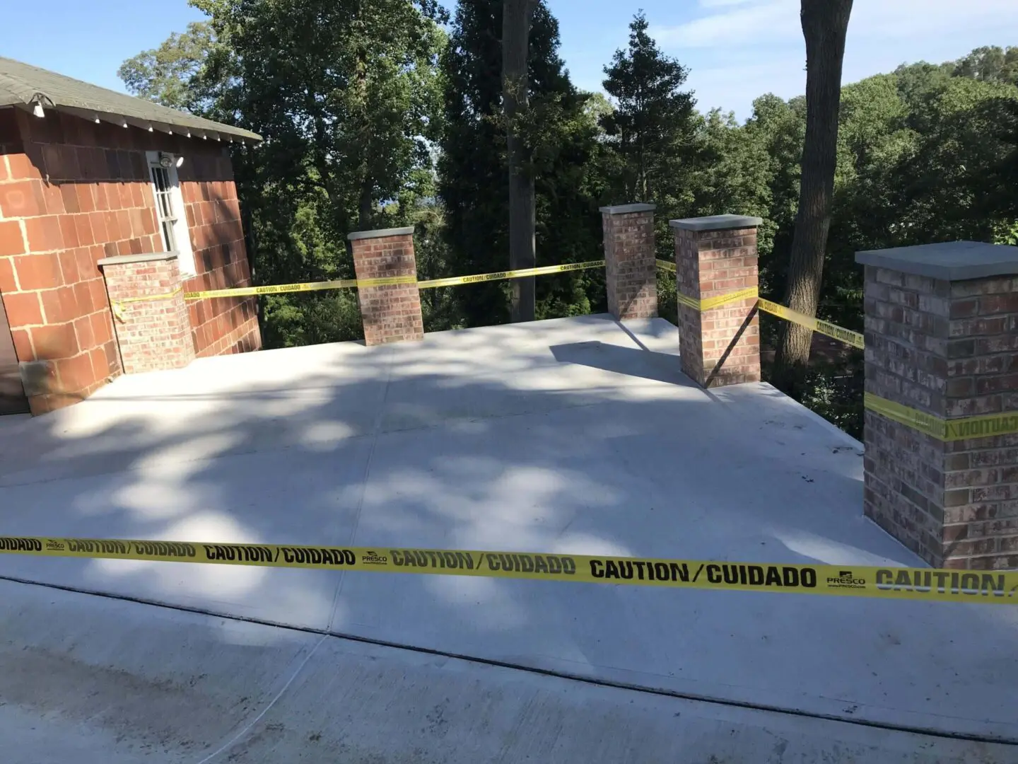 Freshly poured concrete sectioned off with caution tape in a residential area.