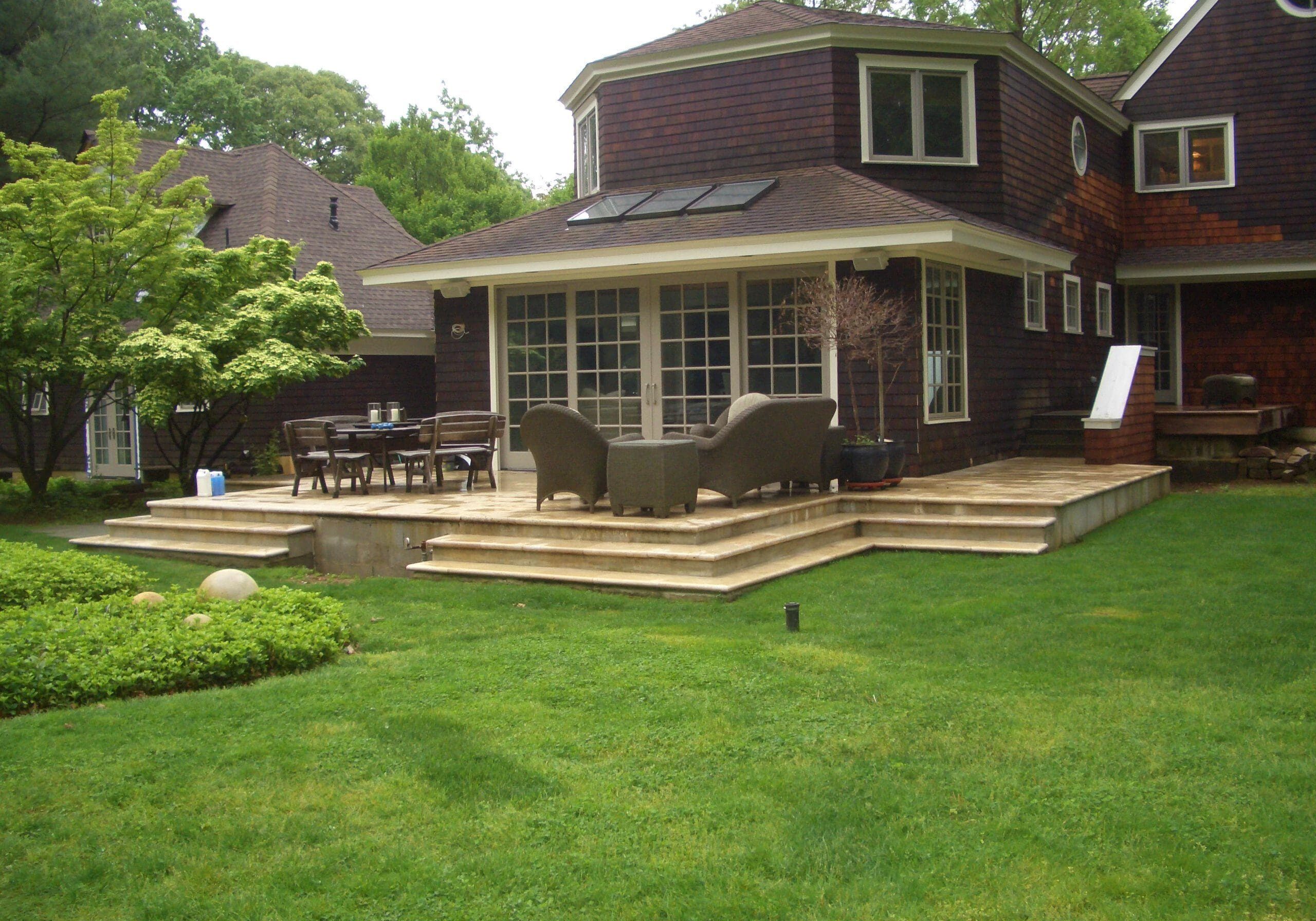 A spacious backyard with a wooden deck attached to a two-story house.